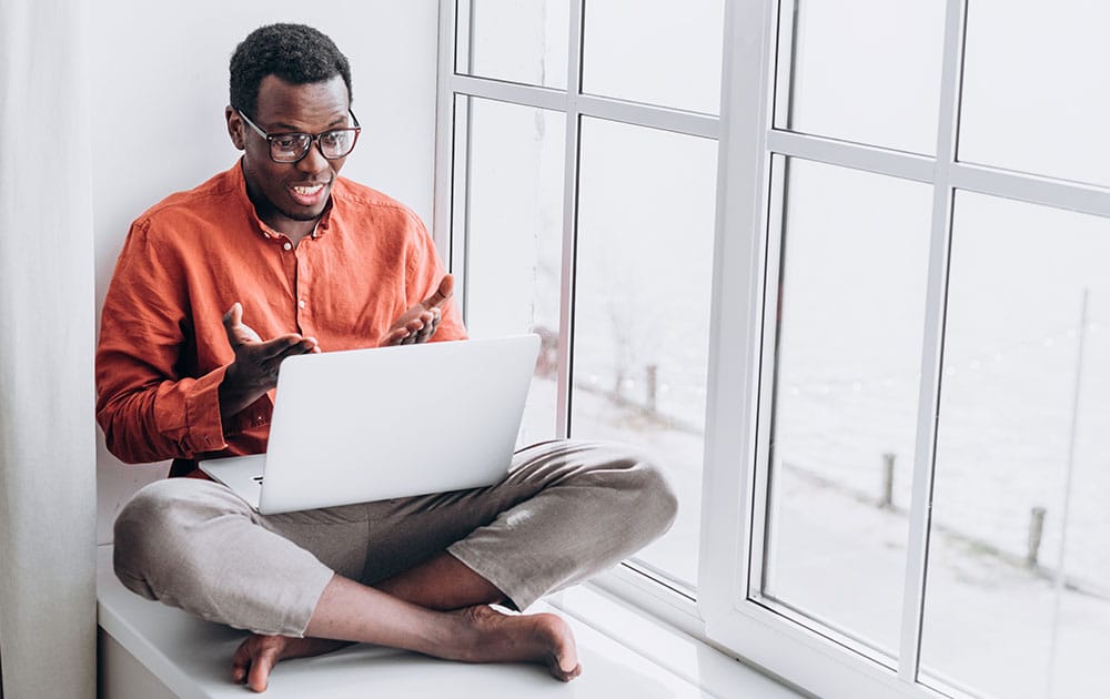 guy sitting with laptop wearing orange shirt
